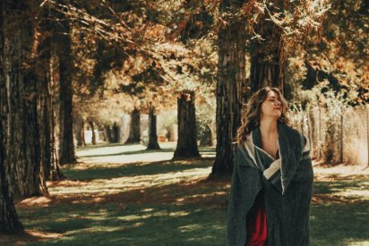 Femme se réconfortant dans un plaid au milieu d'une forêt en automne